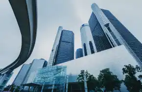 Modern skyscrapers and urban architecture under a cloudy sky in a bustling city.